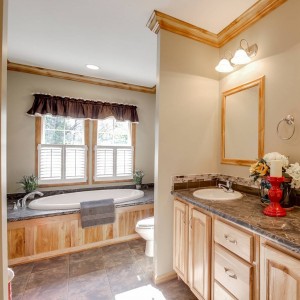 Photo of manufactured home bathroom double vanity with view to large white tub and bright windows