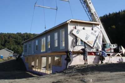 A photo of a construction crane installing a single-wide home in Vermont.