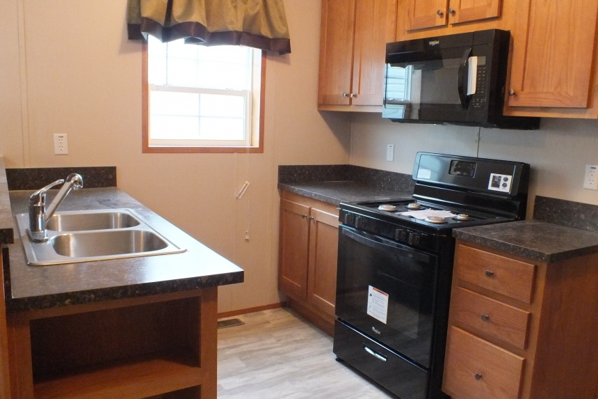 294 stock model single wide home kitchen A Photo Of Stock Model 294 Single Wide Home Kitchen With Sink, Counter, Wood Cabinets And Black Stove