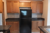 294 stock model single wide home refrigerator A Photo Of Stock Model 294 Single Wide Home Kitchen With Black Refrigerator And Wood Cabinets.