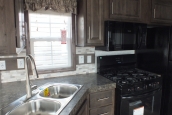 The Park Model 7 manufactured home kitchen sink and bright window A Photo Of Park Model 8 Manufactured Home Kitchen Sink And Bright Window With Black Stove And Wooden Cabinets.