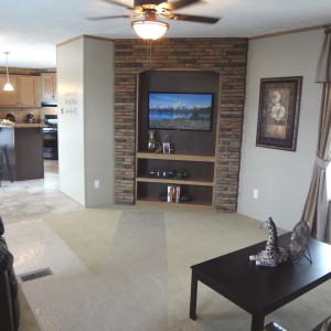 Photo of manufactured home interior furnished living room with entertainment console looking into kitchen