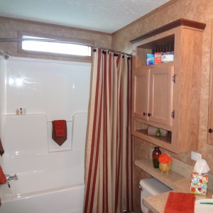 Photo of manufactured home bathroom wood cabinets with view to shower and narrow window