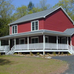 Photo of manufactured home red exterior with driveway and large porch