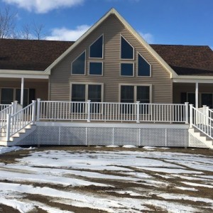 Photo of manufactured home brown exterior with snow  two stories and large deck